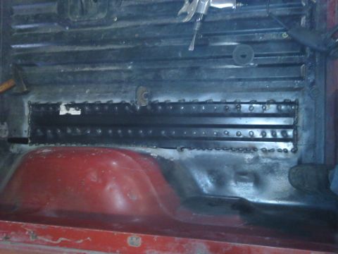 1978 Ford Bronco - Close-up of the interior floor of a vehicle, showing metal reinforcement work and a red wheel well.