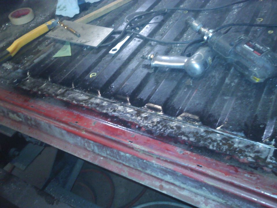 Red truck bed with a drill, air hammer, and tape