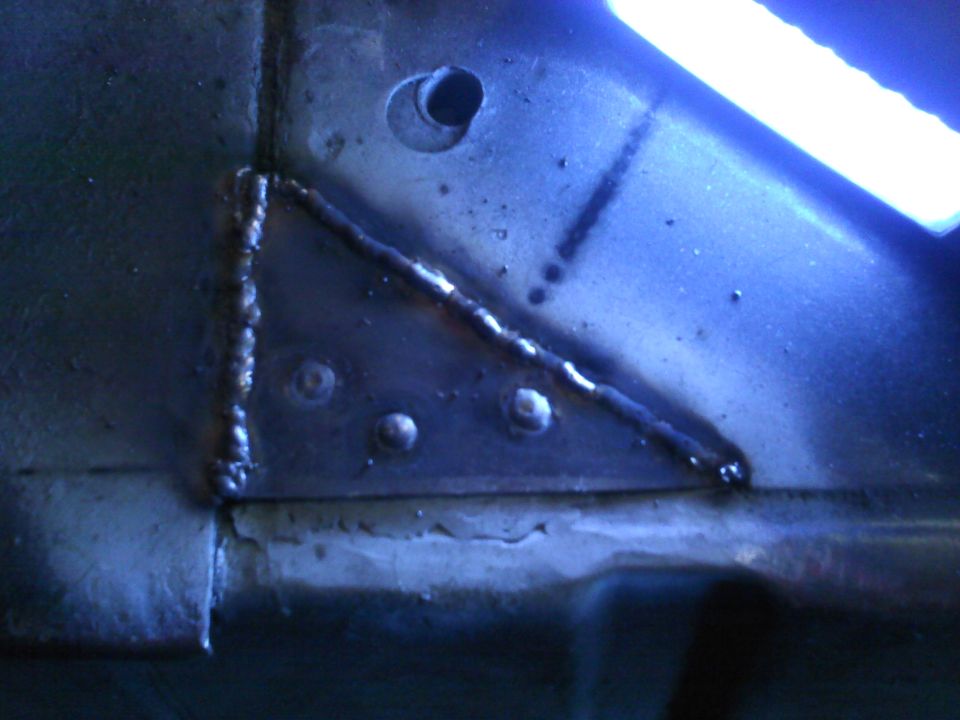 Close-up of welded metal on a vehicle frame. Shows rivets and a drilled hole