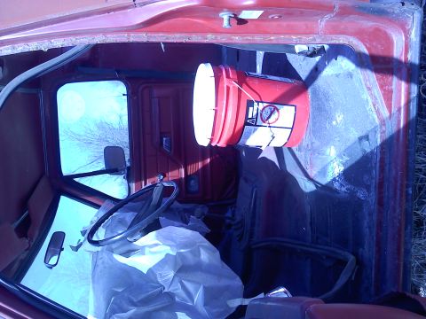 1978 Ford Bronco - Interior view of a red truck cab with a bucket hanging and items covered in plastic.