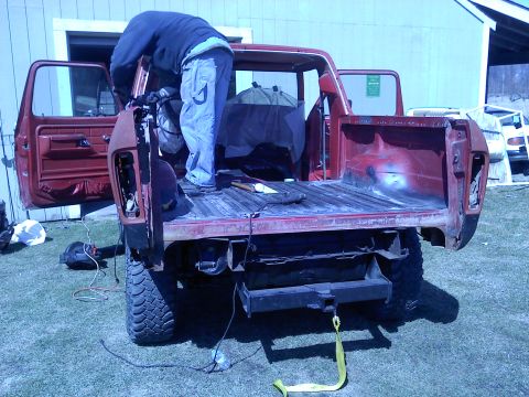 1978 Ford Bronco - Person working on the rear of a red 1978 Ford Bronco with the bed disassembled.