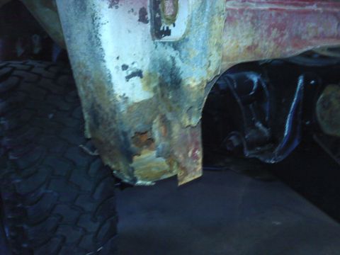 1978 Ford Bronco - Close-up view of significant rust on the wheel well and suspension components of a vehicle.