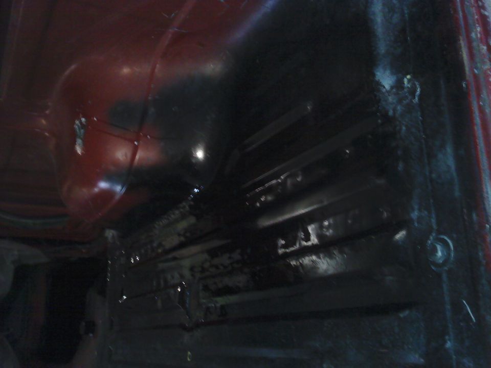 Red and black vehicle interior floor with visible structural ribs and a circular wheel well