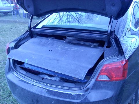 1978 Ford Bronco - Open car trunk reveals a blue mat and stored items, with a red taillight on the right side.