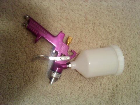 1978 Ford Bronco - A purple spray gun with a white cup sits on a carpeted surface.