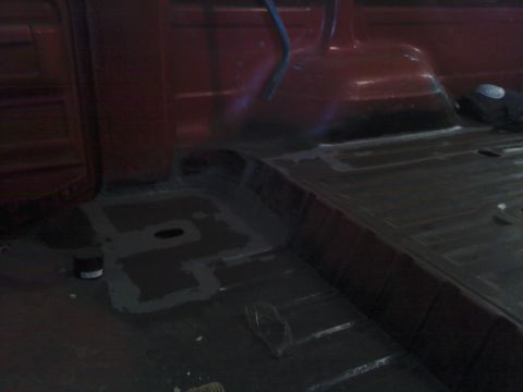 1978 Ford Bronco - The interior floor of a red vehicle shows areas treated with gray sealant.