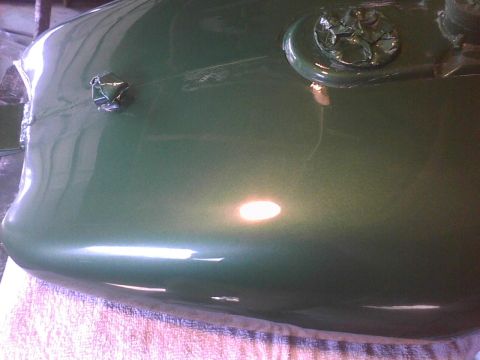 2003 Ford Crown Victoria - Close-up of a taped car hood emblem on a green painted surface.