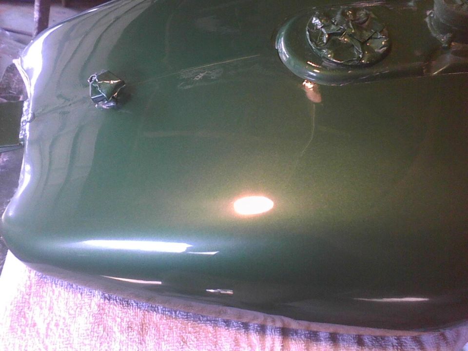Green car hood with a silver emblem covered in tape