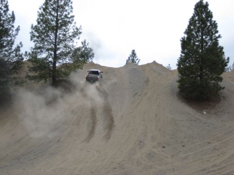 2005 Jeep Wrangler - An SUV navigates a steep, dusty incline, leaving tire tracks in its wake.