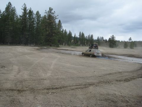 2005 Jeep Wrangler - Two vehicles navigate a dusty off-road course under a cloudy sky.