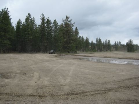 2005 Jeep Wrangler - A black 2005 Jeep Wrangler is parked in a dusty, open area with a line of trees in the background.