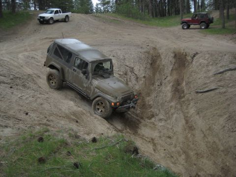 2005 Jeep Wrangler - A 2005 Jeep Wrangler navigates a challenging off-road trail with other vehicles present.