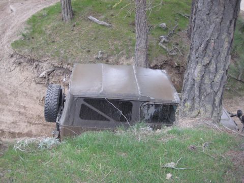 2005 Jeep Wrangler - A brown Jeep Wrangler is stuck in a ditch, with its spare tire mounted on the side.