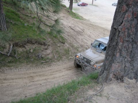 2005 Jeep Wrangler - A Jeep Wrangler navigates a sandy off-road trail, with other vehicles visible in the distance.