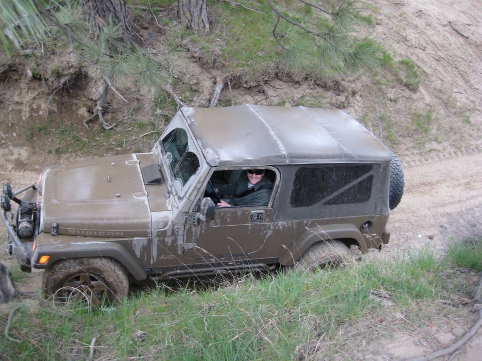 Brown 2005 Jeep Wrangler off-roading in mud, seen from a 3/4 front angle