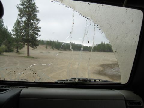 2005 Jeep Wrangler - Looking out through a dirty windshield at an outdoor scene with trees and sandy terrain.