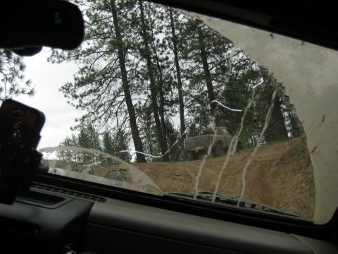 2005 Jeep Wrangler - A pickup truck drives up a dirt incline in a wooded area, viewed from the interior of another vehicle.