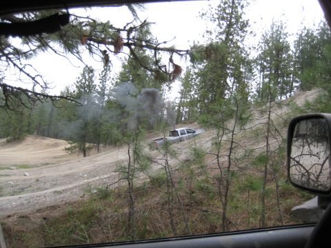 2005 Jeep Wrangler - Pickup truck stuck on a hill, producing smoke. Off-road scene with trees and dirt.