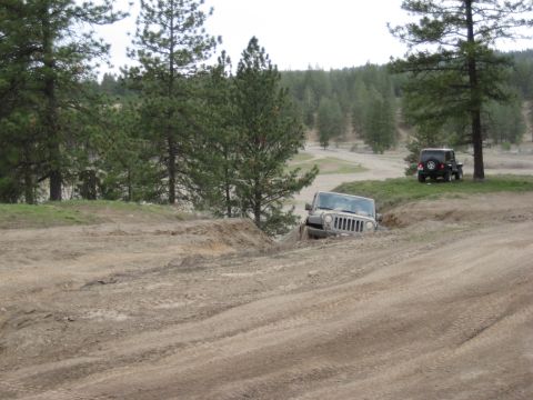2005 Jeep Wrangler - Two Jeep Wranglers navigate a dirt track in a wooded, hilly area.