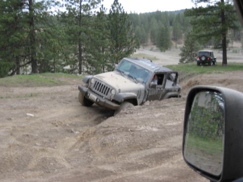 2005 Jeep Wrangler - A Jeep Wrangler navigates a challenging off-road course, getting stuck in a muddy rut while another Jeep observes.