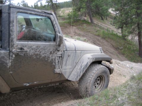 2005 Jeep Wrangler - A mud-splattered Jeep Wrangler navigates an off-road trail.