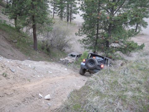2005 Jeep Wrangler - Two Jeep Wranglers navigate a challenging dirt path in a wooded, hilly terrain.