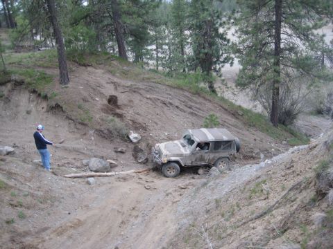 2005 Jeep Wrangler - A person stands on a hillside, watching a Jeep Wrangler navigate a steep, muddy off-road path.