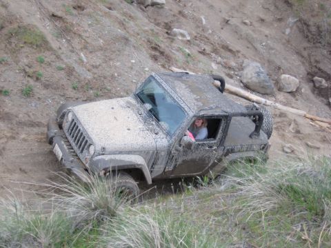 2005 Jeep Wrangler - A mud-covered 2005 Jeep Wrangler navigates an off-road trail.