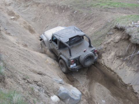 2005 Jeep Wrangler - A Jeep Wrangler navigates a steep dirt incline, kicking up dust as it goes.