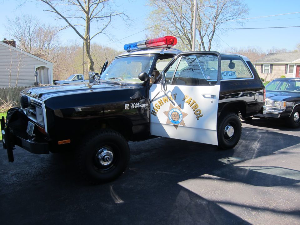 Black police SUV with open door, light bar, and "HIGHWAY PATROL" text