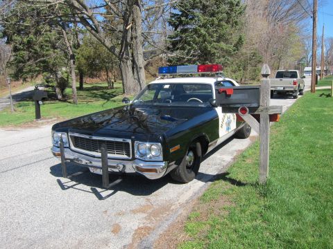 1991 Ford LTD Crown Victoria - A black and white police car with a light bar is parked on the side of the road next to a mailbox, with another vehicle visible in the back…
