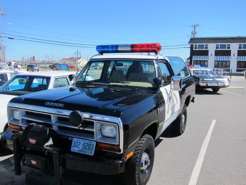 1991 Ford LTD Crown Victoria - A black Dodge Ram SUV with a light bar and police markings is parked in a lot.