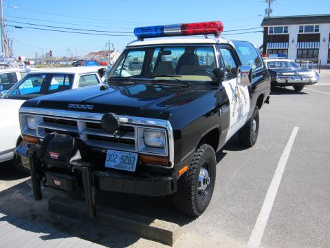 1991 Ford LTD Crown Victoria - A black Dodge Ram police SUV is parked next to another police car.