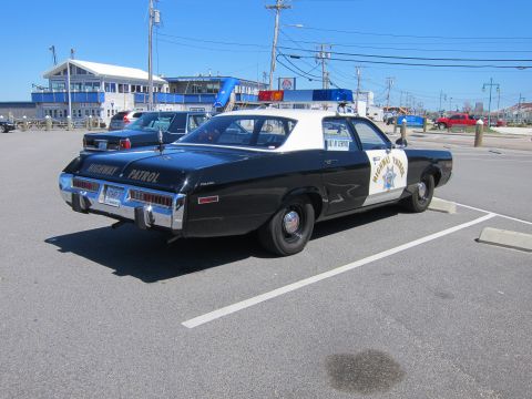 1991 Ford LTD Crown Victoria - This vintage highway patrol car is parked in a lot with a building in the background.