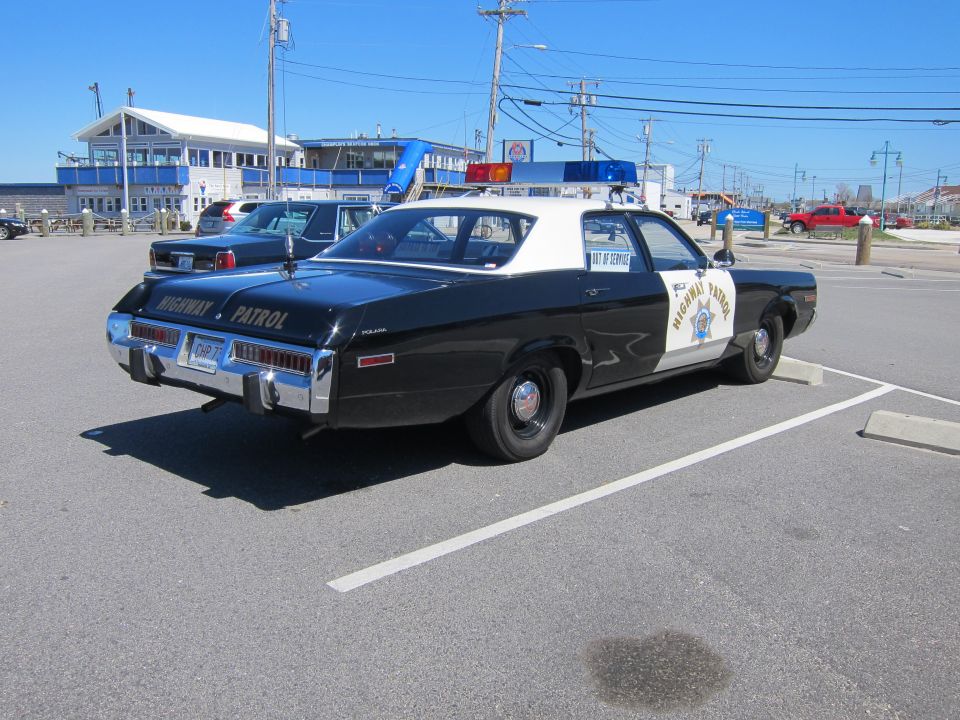 Black and white highway patrol car parked, 'HIGHWAY PATROL' on trunk lid