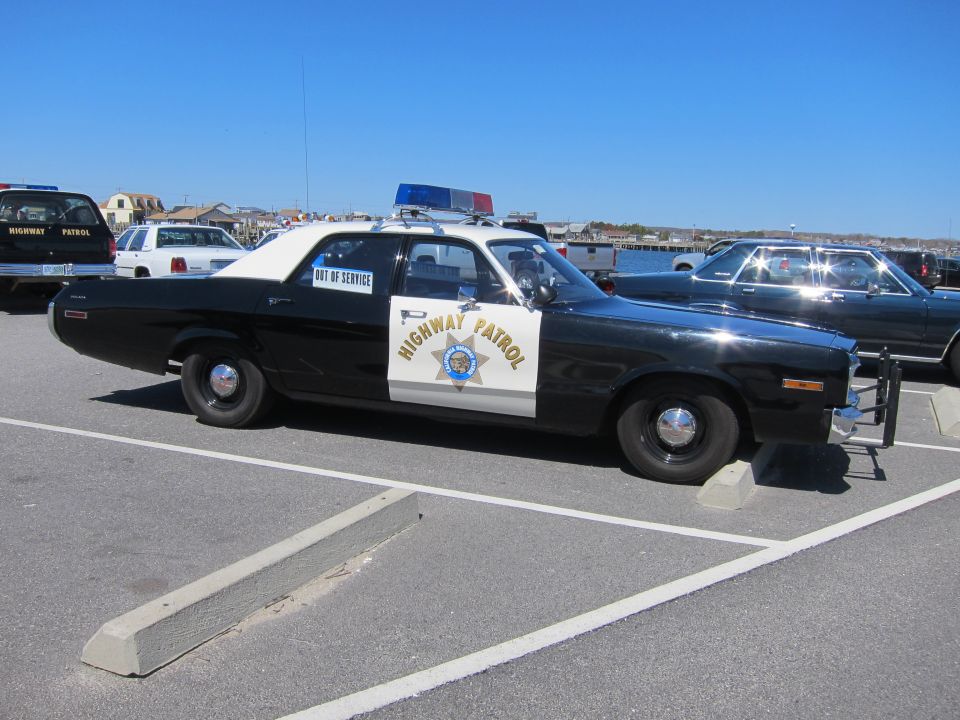 Black and white police car with 'HIGHWAY PATROL' on the door and 'OUT OF SERVICE' on the window
