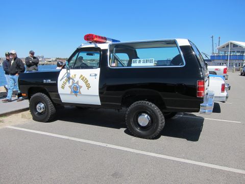 1991 Ford LTD Crown Victoria - This Dodge Ramcharger police SUV is parked outdoors with other vehicles nearby.