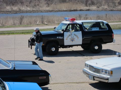 1991 Ford LTD Crown Victoria - This Dodge Ram police SUV is parked next to other vehicles, with a body of water in the background.