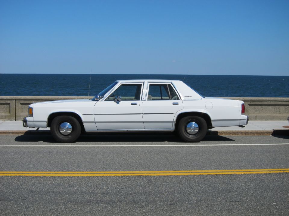White 1991 Ford Crown Victoria LTD sedan, side view, parked by the ocean