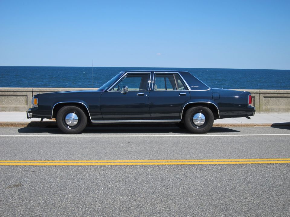 dark blue sedan parked by the ocean, side view