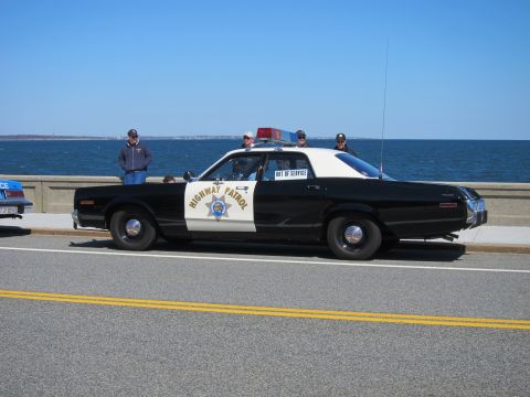 1991 Ford LTD Crown Victoria - A vintage police car with "OUT OF SERVICE" displayed on the rear window is parked near the water.