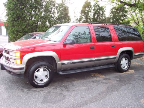 1999 Chevrolet Suburban - Red 1999 Chevrolet Suburban with tan lower body trim and roof rack.