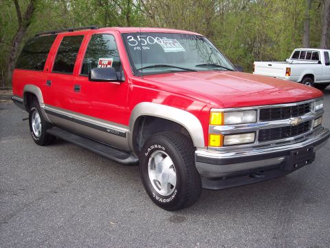 1999 Chevrolet Suburban - This red Chevrolet Suburban is parked outdoors with a "FOR SALE" sign on the windshield.