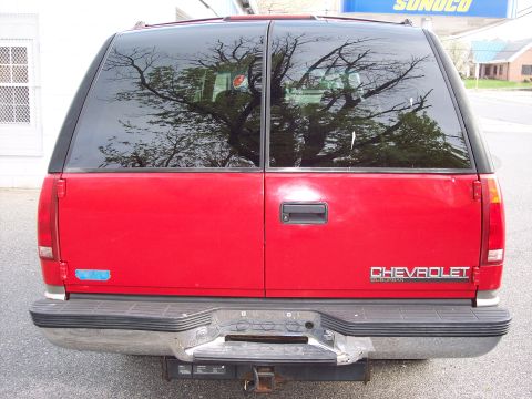 1999 Chevrolet Suburban - Rear view of a red 1999 Chevrolet Suburban, displaying its dual rear doors and chrome bumper.