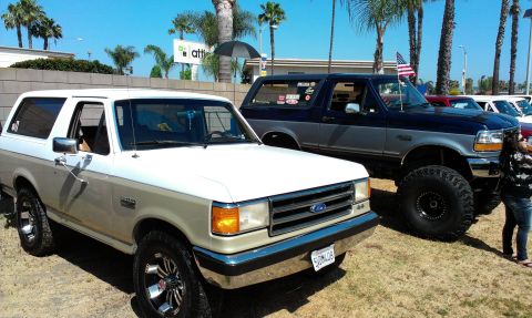 1994 Ford Bronco - Two Ford Broncos are parked next to each other on a sunny day.