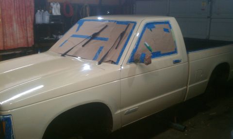 1991 Chevrolet S10 - A pickup truck is being prepared for a paint job, with masking tape covering the windows.