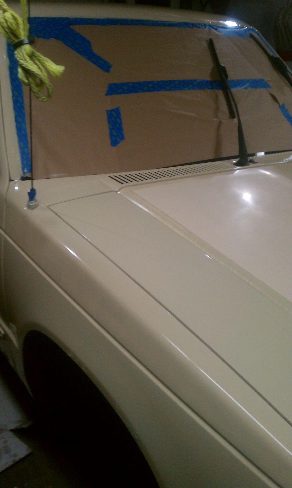 Cream colored truck hood and fender with windshield taped off
