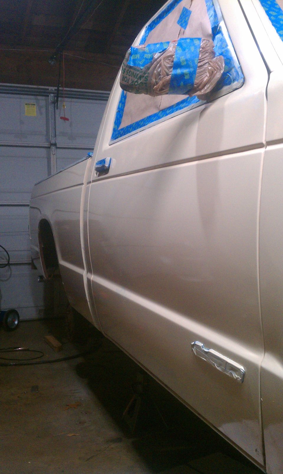 Side view of beige 1991 Chevrolet S10 pickup truck with masking tape on window