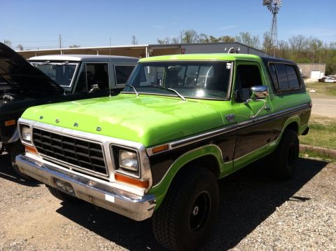 1990 Ford Bronco - Two Ford Broncos are parked outside on a sunny day, one is lime green and black.