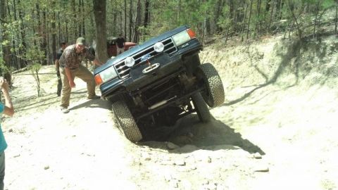 1990 Ford Bronco - This Ford Bronco is navigating a steep, rocky incline on a wooded trail.